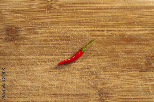 single red chili pepper from top on the cutboard