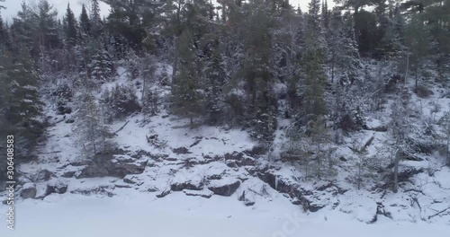 4K aerial flight up a snow covered rock face and forest with ice fog.