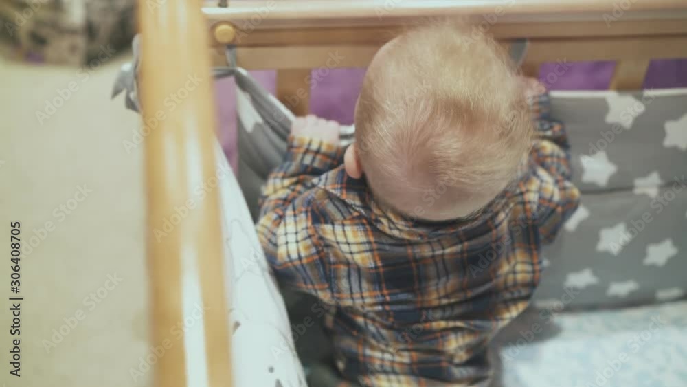 cute little baby in checkered shirt plays in rocking soft cot with star blanket in light room closeup view from above cute little baby in checkered shirt plays in rocking soft cot with star blanket in light room closeup view from above