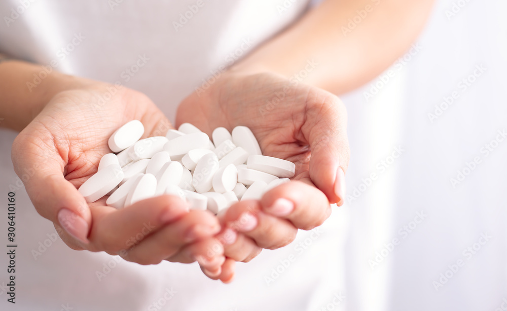 Woman holds a handful of pills Woman holds a handful of pills