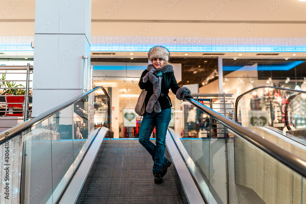 attractive woman is going down the escalators in a department store
