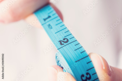 Person with tape measure shows 3 inch length, three inch, closeup, toned