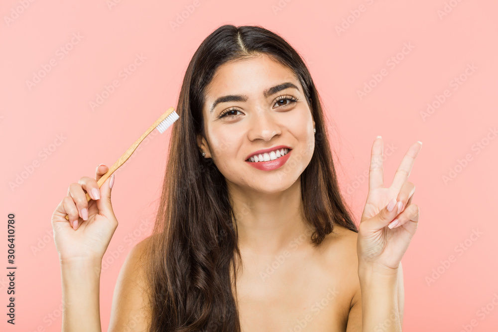Young indian woman holding a toothbrush showing number two with fingers. Young indian woman holding a toothbrush showing number two with fingers.
