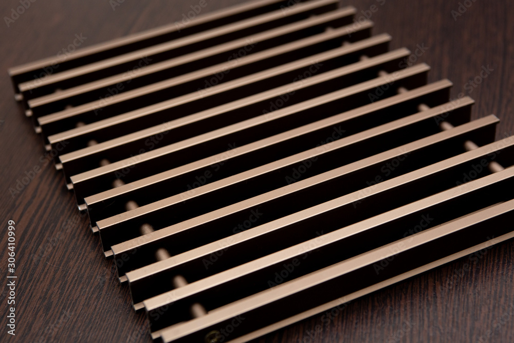 On a dark table lies a grate of chocolate-burgundy metal planks connected by inserts. On a dark table lies a grate of chocolate-burgundy metal planks connected by inserts.