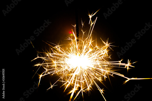 Sparkler in honor of the holiday on a black background. Merry Christmas