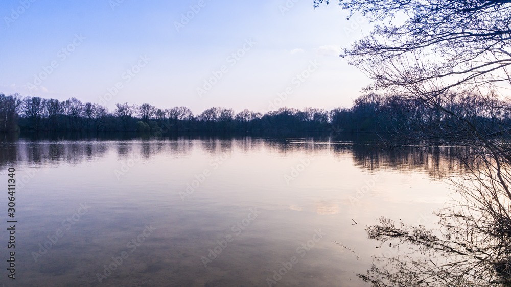 Landschaft mit von Bäumen gesäumten See bei Sonnenuntergang