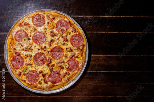 Homemade hot pepperoni pizza ready to eat on a wooden table and aluminum tray