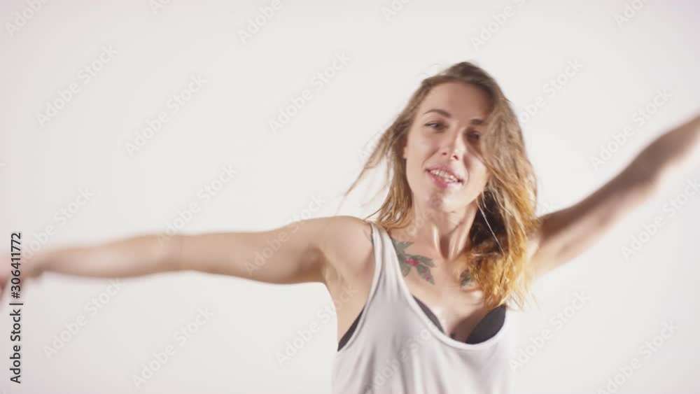 Waist up studio shot of young beautiful sweaty woman with wet hair and tattoos on chest looking at camera and performing seductive dance against white background Waist up studio shot of young beautiful sweaty woman with wet hair and tattoos on chest looking at camera and performing seductive dance against white background