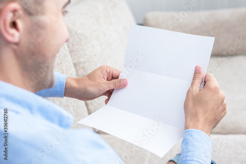Man reading a letter at the couch, men's hands, close up, rear view, copy space, toned