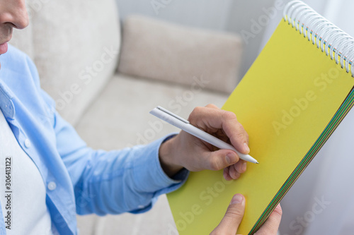 Man writing in a notebook pen, man doing homework, cropped image, copy space, toned