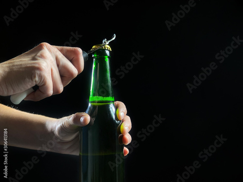 Woman's hands is opening green bottle of beer, slow motion video