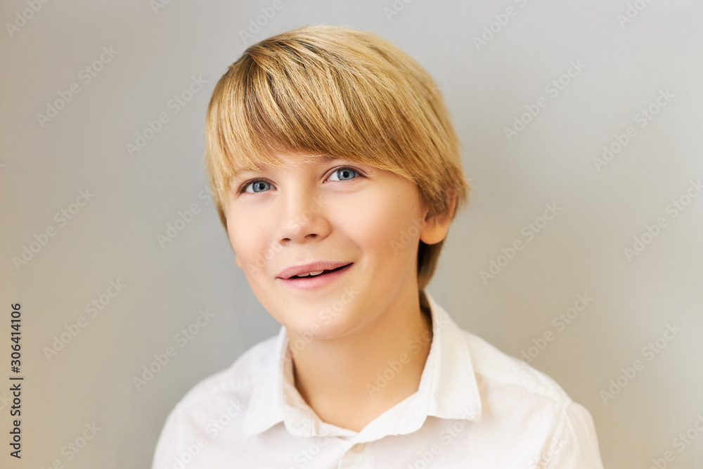 Φωτογραφία Horizontal portrait of attractive blue eyed Caucasian schoolboy with stylish hairdo smiling joyfully having delighted excited facial expression, fascinated with something amazing