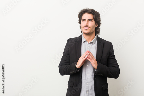 Young business man against a white background making up plan in mind, setting up an idea.