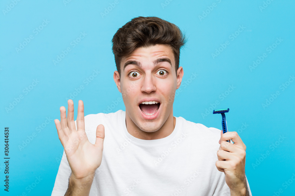 Young caucasian man holding a razor blade celebrating a victory or success Young caucasian man holding a razor blade celebrating a victory or success