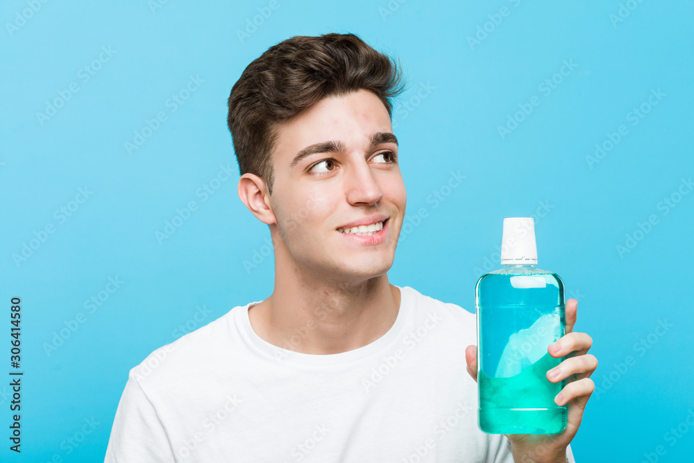 Young caucasian man holding a mouthwash smiling confident with crossed arms. Young caucasian man holding a mouthwash smiling confident with crossed arms.
