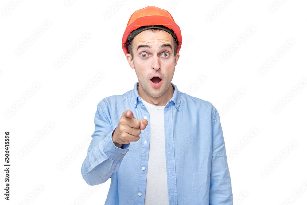 Amazed builder in hardhat indicates at you, isolated background, copy space Amazed builder in hardhat indicates at you, isolated background, copy space