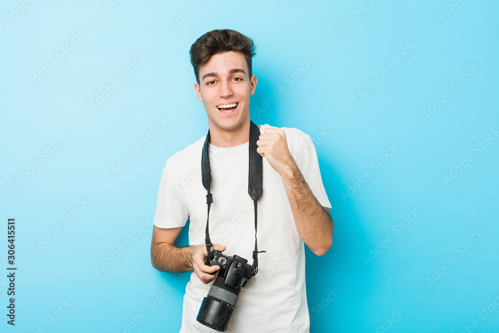 Young caucasian photographer man holding a camera cheering carefree and excited. Victory concept. Young caucasian photographer man holding a camera cheering carefree and excited. Victory concept.