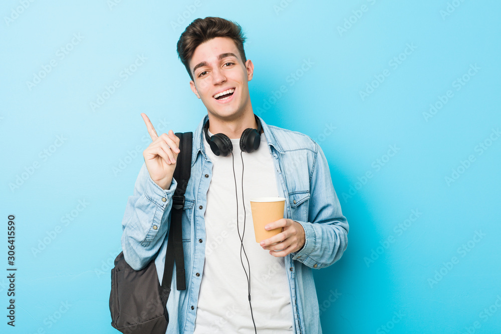 Young caucasian student man holding a take away coffee smiling cheerfully pointing with forefinger away. Young caucasian student man holding a take away coffee smiling cheerfully pointing with forefinger away.