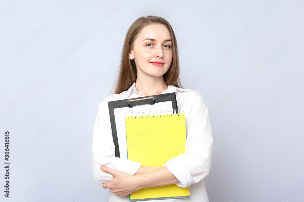 Beautiful girl student with notebooks. Concept of education. Portrait, grey background, copy space, slogan, toned Beautiful girl student with notebooks. Concept of education. Portrait, grey background, copy space, slogan, toned