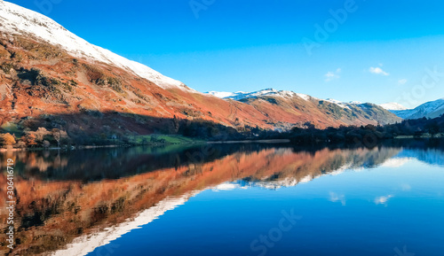 Ullswater lake with snow capped mountains surrounding the second largest lake in the Lake District, Cumbria, UK. Autumn lake reflections on a peaceful day with still waters. 