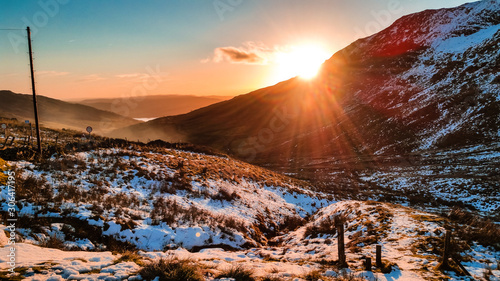 Kirkstone Pass in Cumbria is Lake District's highest pass that is open to motor traffic and it connects Ambleside to Patterdale in the Ullswater Valley. The A592 road. Snowy winter sunset.