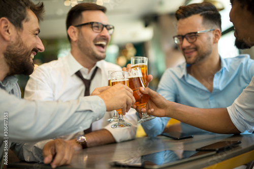 Foto Businessmen sit in pub and drinking beer after work