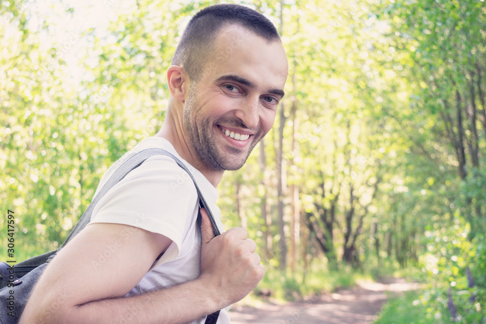 Cheerful man with a backpack goes on the road and smiling, portrait, toned Cheerful man with a backpack goes on the road and smiling, portrait, toned