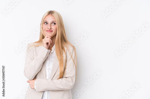 Young business blonde woman on white background looking sideways with doubtful and skeptical expression.