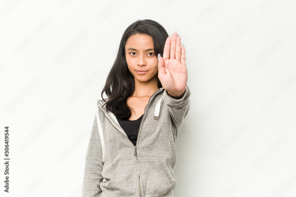Young fitness chinese woman standing with outstretched hand showing stop sign, preventing you. Young fitness chinese woman standing with outstretched hand showing stop sign, preventing you.