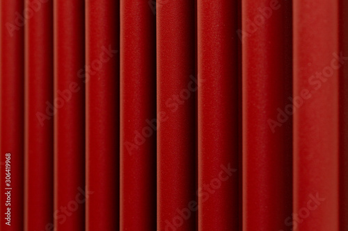 Abstract background in the form of vertical bright red wide stripes of a porous structure close-up.