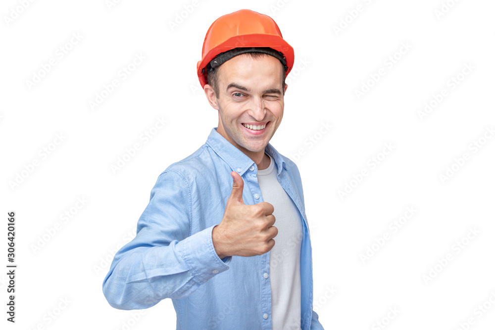 Cheerful builder in hardhat, man winks and shows thumb up, isolated background, copy space Cheerful builder in hardhat, man winks and shows thumb up, isolated background, copy space