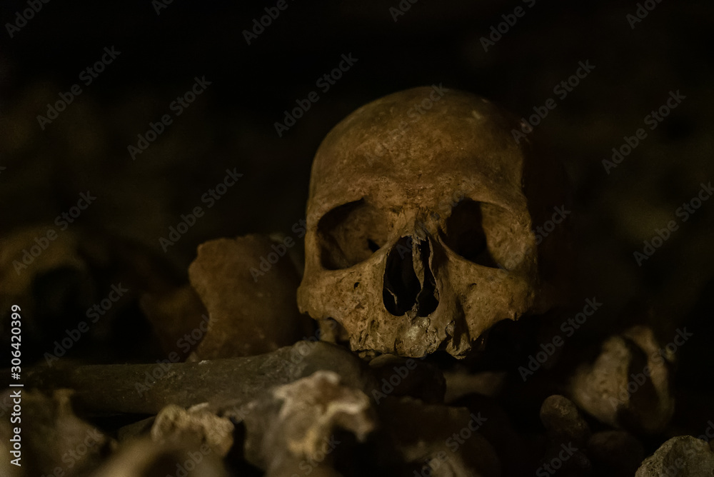 Skulls and bones in catacombs. Old broken skull placed on the bones. Underground cemetery
