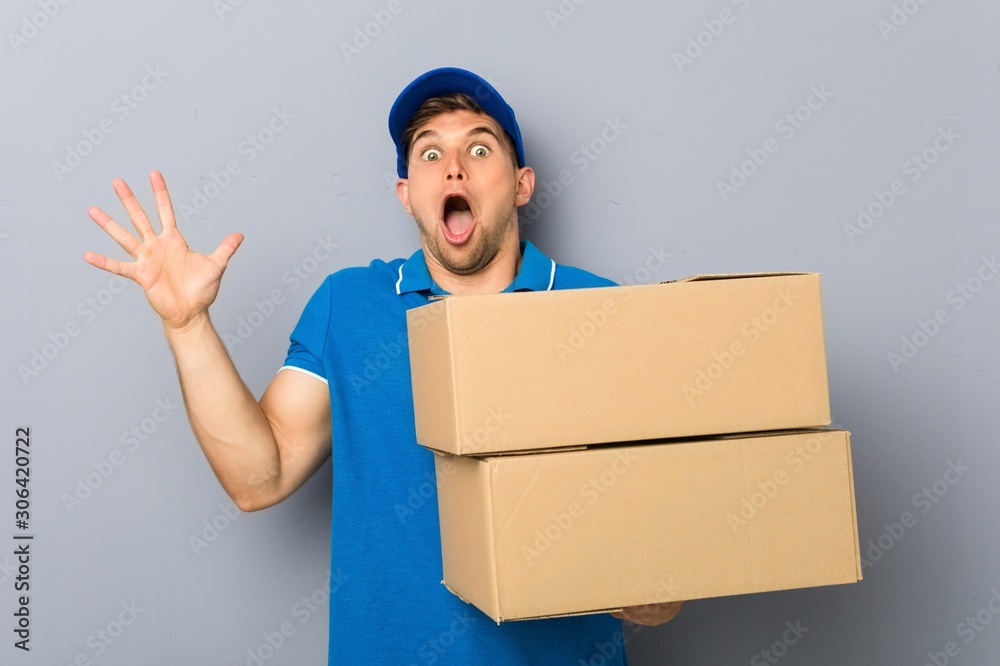 Young man delivering packages celebrating a victory or success Young man delivering packages celebrating a victory or success