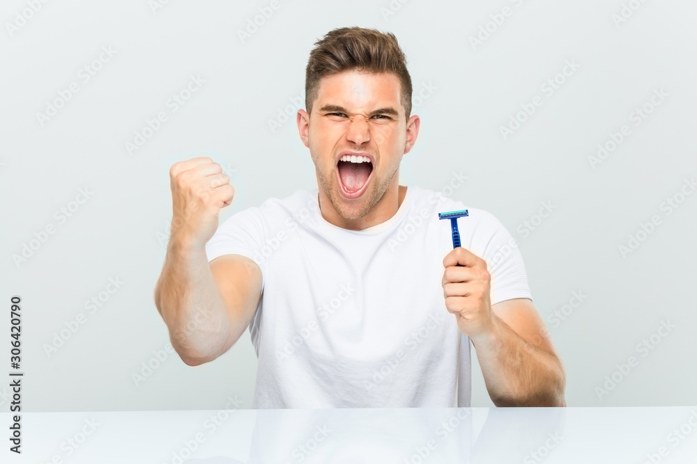 Young man holding a razor blade cheering carefree and excited. Victory concept. Young man holding a razor blade cheering carefree and excited. Victory concept.