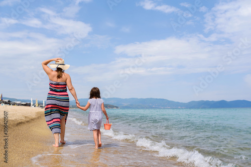 Mother And Little Daughter Walking Along Beautiful Beach 