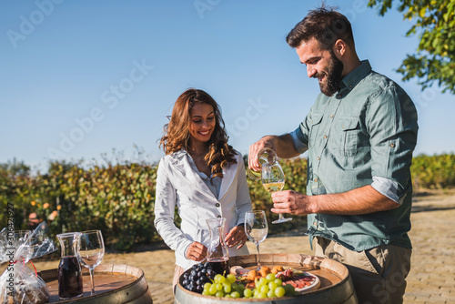 Young smiling man and woman tasting wine at winery vineyard - Young people enjoying harvest time together