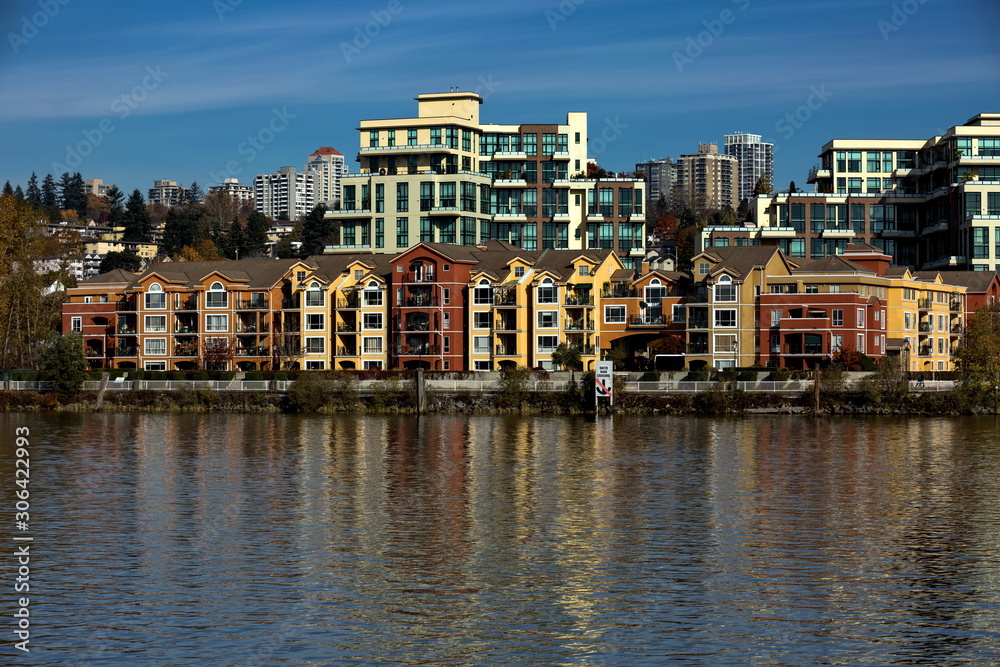 Residential area on the promenade of New Westminster, a block of multi-stores buildings near the riverbank against a blue sky
