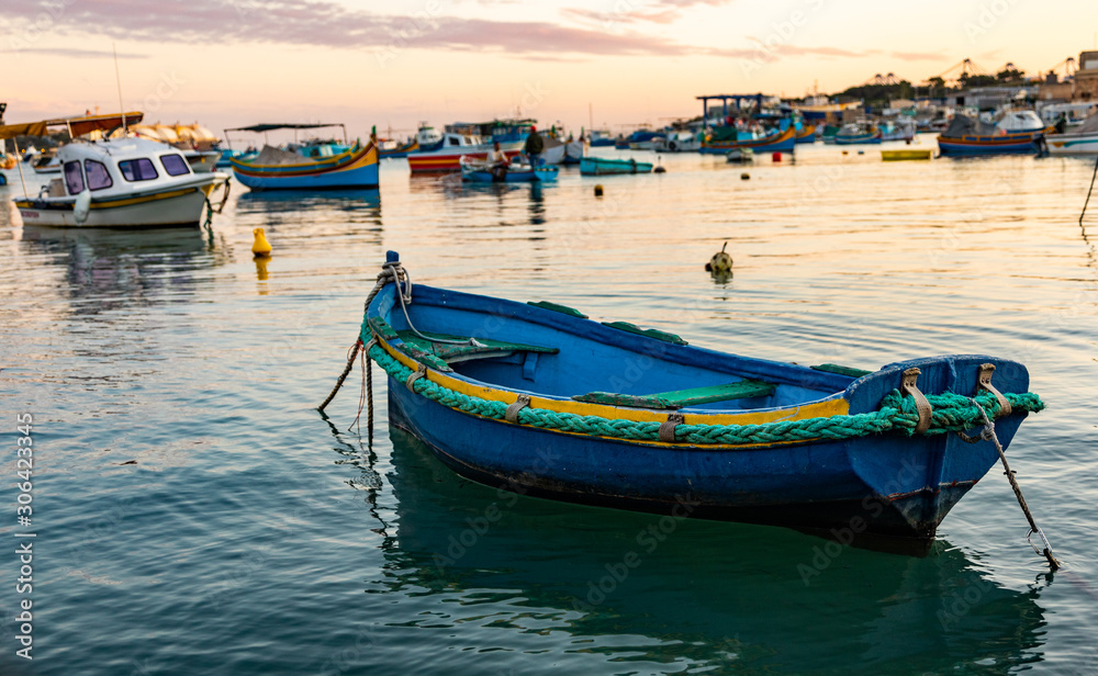 Old colorful fisherman boat in the harbor of Marsaxlokk in Malta on sunset