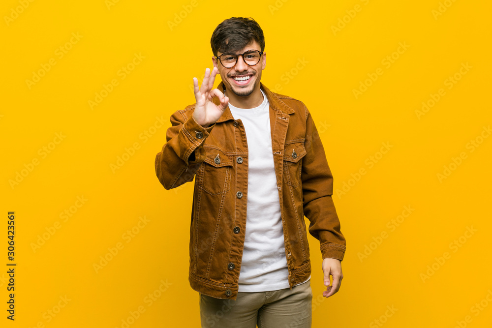 Fototapeta premium Young hispanic casual man cheerful and confident showing ok gesture.