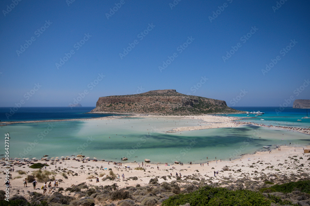 Tourists having fun on the sands and turquoise waters of balos lagoon at crete, greece