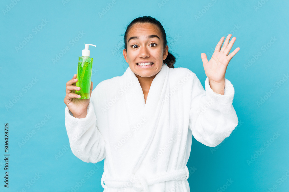 Young mixed race indian holding an aloe vera bottle celebrating a victory or success Young mixed race indian holding an aloe vera bottle celebrating a victory or success