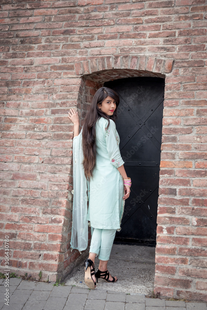 Indian girl in traditional dress stand at the entrance to the house.