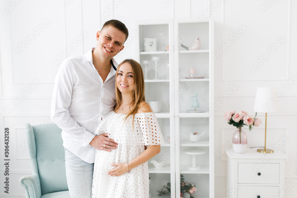 Young pregnant woman with husband in room. Woman waiting for a newborn baby. Young pregnant woman with husband in room. Woman waiting for a newborn baby.