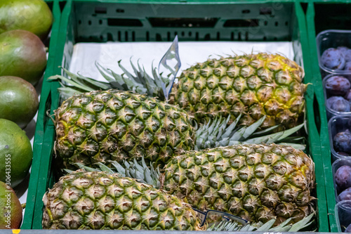 Obststand mit frischen Ananas verkauft exotische Früchte für Vegetarier und Veganer und ihre gesunde Ernährung mit frischen Früchten und vitaminreicher Rohkkost photo