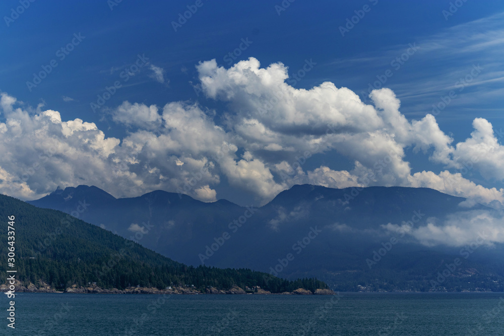 Coastal Pacific mountains as viewed from the Thick white clouds drift over the mountain on the Pacific Ocean, BC, Canada