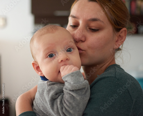 Pretty woman holding a three months baby with blue eyes in her arms