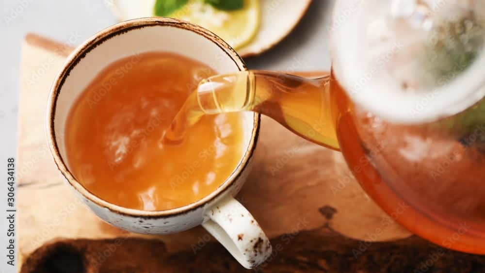 Pouring green tea in cup. Glass tea pot. Hot healthy drink