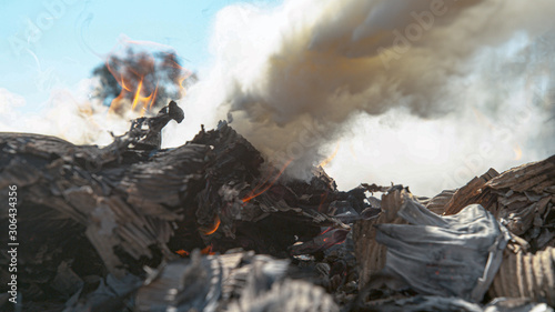 MACRO: Heap of cardboard burning in backyard is extinguished by white powder.
