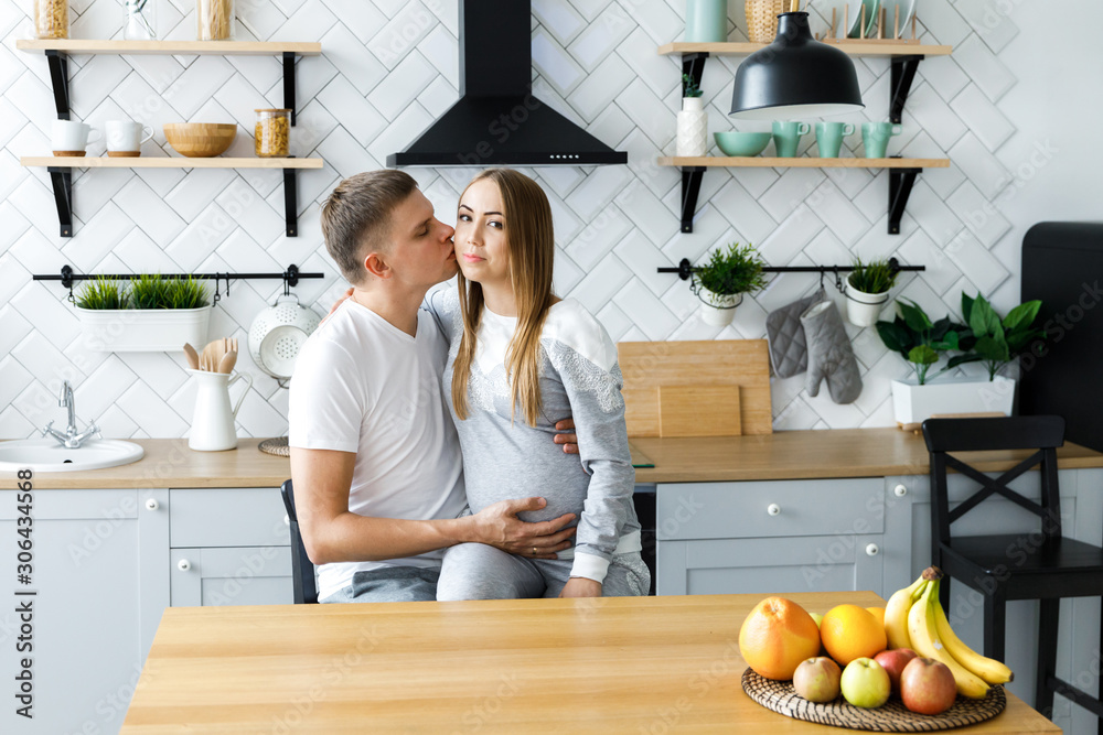 Young couple - man and woman expecting a baby, spend time in the kitchen. Awaiting the birth of a baby Young couple - man and woman expecting a baby, spend time in the kitchen. Awaiting the birth of a baby