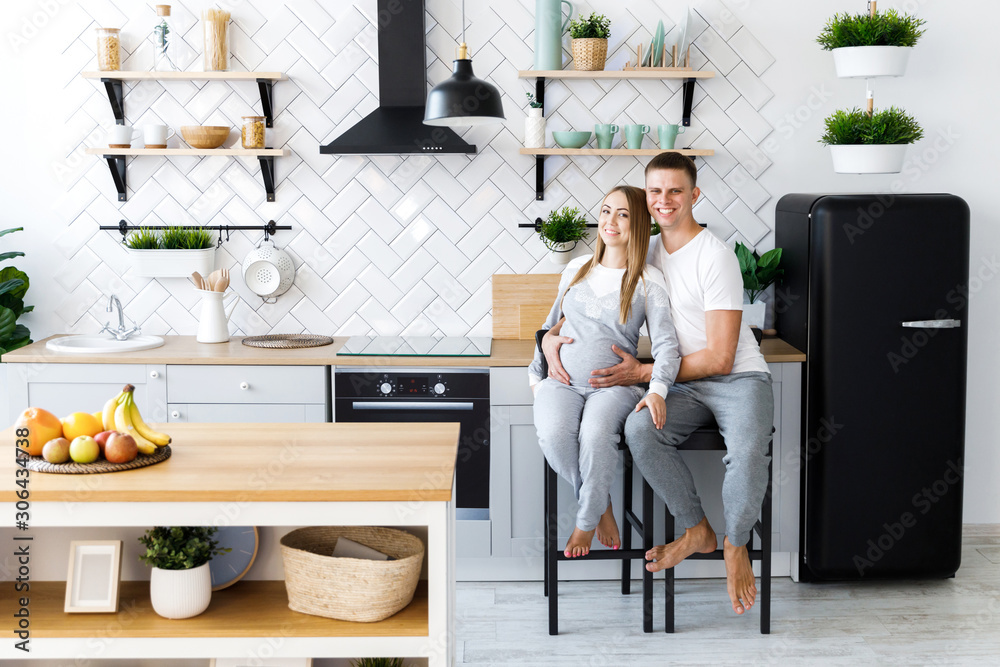 Young couple - man and woman expecting a baby, spend time in the kitchen. Awaiting the birth of a baby Young couple - man and woman expecting a baby, spend time in the kitchen. Awaiting the birth of a baby